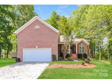 Inviting brick home featuring a two-car garage, a well-manicured lawn, and lush landscaping at 2104 Congress Ct, Kannapolis, NC 28083