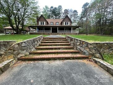Charming two-story home with brick stairs, a large front porch, and mature trees at 3452 Odell School Rd, Concord, NC 28027