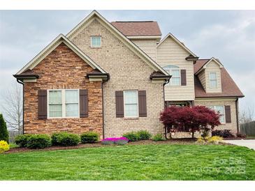 Charming two-story home with a well-manicured lawn and stone and brick exterior, exuding curb appeal at 641 Weyburn Nw Dr, Concord, NC 28027