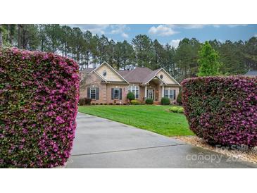 Charming brick home with manicured lawn, blooming bushes, and concrete driveway at 7268 Kiskadee Dr, Denver, NC 28037