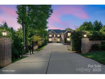 Elegant home with gated entrance, long driveway, and manicured landscaping visible at dusk at 7944 Park Rd, Charlotte, NC 28210