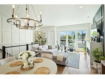 Bright and airy living room features hardwood floors, large windows, and stylish chandelier at 1105 Reece Rd, Charlotte, NC 28209