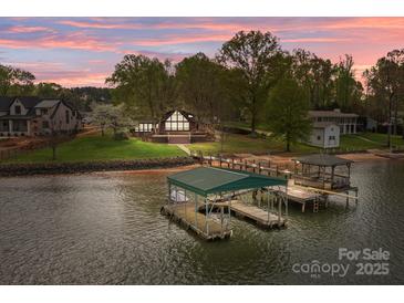 Stunning waterfront home featuring a private boat dock and lush landscaping at sunset at 477 Big Indian Loop, Mooresville, NC 28117