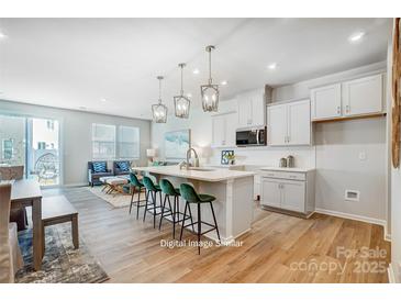 Modern kitchen features white cabinets, stainless appliances, an island with seating, and an open floor plan at 6427 Mallow Crossing Ln, Charlotte, NC 28213