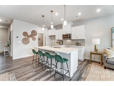 Bright kitchen boasts white cabinetry, an island with seating, and modern pendant lighting at 7144 Hodges Meadow Ln, Charlotte, NC 28213