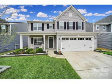 Charming two-story home boasts a well-manicured lawn, covered porch, and a two-car garage at 1018 Hinson Forest Rd, Monroe, NC 28110