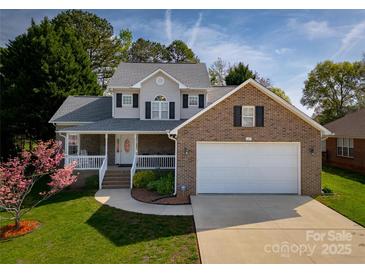 Charming two-story home with a brick facade, covered porch, manicured lawn, and attached two-car garage at 121 Shagbark Ln, Mooresville, NC 28115