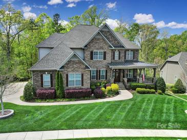 Beautiful two-story brick home with a manicured lawn and a charming front porch, perfect for relaxing and enjoying the outdoors at 141 Forsythia Ln, Tega Cay, SC 29708