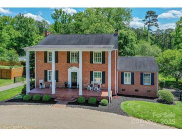 Classic brick home with a charming front porch, rocking chairs, and manicured landscaping at 203 Mt Holly Huntersville Rd, Huntersville, NC 28078