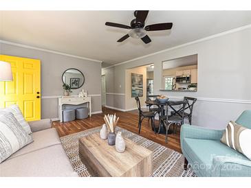 Bright living room boasts a yellow door, hardwood floors, dining table, and an open view into the kitchen at 3701 Slagle Dr, Charlotte, NC 28215