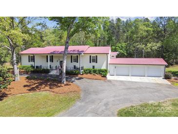 Beautiful white brick home featuring a red roof and a spacious three-car garage at 4205 Cahnnas Way, Waxhaw, NC 28173