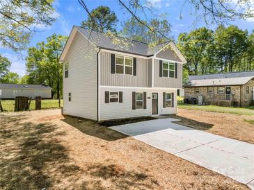 Charming two-story home features a gray siding, black shutters, and a concrete driveway leading to the front door at 505 E Robinson St, Dallas, NC 28034