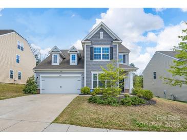 Charming two-story home featuring a manicured lawn, a two-car garage, and appealing architectural details at 16803 Cozy Cove Rd, Charlotte, NC 28278