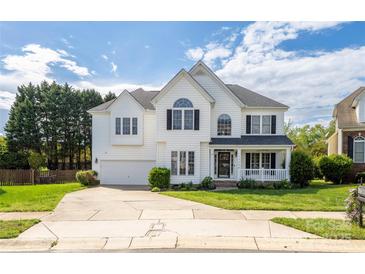 Inviting two-story home with a manicured lawn, attached garage, and a charming front porch at 17309 Knoxwood Dr, Huntersville, NC 28078