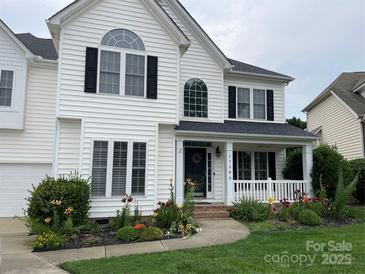 Charming two-story home with white siding, black shutters, covered porch, and inviting front yard flower garden at 17309 Knoxwood Dr, Huntersville, NC 28078