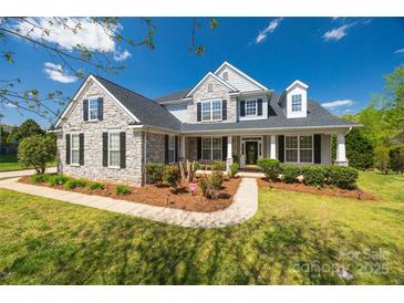 Charming two-story home featuring stone accents, black shutters, a welcoming front porch, and manicured landscaping at 2004 Ptarmigan Ct, Waxhaw, NC 28173