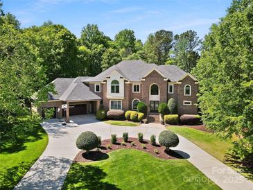Stately brick home boasts lush landscaping, circular drive, and attached garage with a basketball hoop at 5001 Oxfordshire Rd, Waxhaw, NC 28173