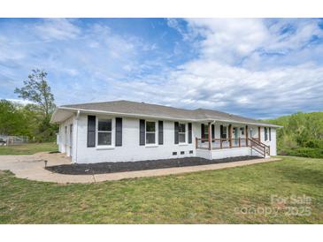 Charming, white, single-story home with dark shutters, wood porch, and well-maintained lawn at 6599 Mcintosh Rd, Stanley, NC 28164