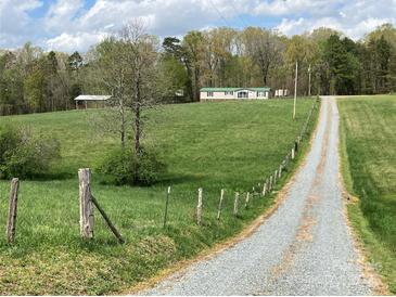 Gravel driveway leads to a single story home with green roof at 13079 Philadelphia Church Rd, Oakboro, NC 28129
