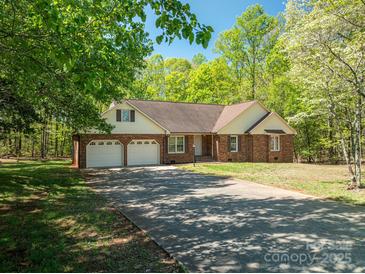 Charming brick home featuring an attached three-car garage and long driveway nestled among beautiful trees at 1478 Smith Farm Rd, Lincolnton, NC 28092