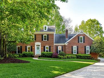 Charming brick home with lush green lawn, mature trees, and manicured landscaping for great curb appeal at 5043 Hickory Lake Ln, Matthews, NC 28105