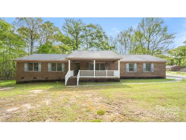 Charming brick home featuring a covered front porch and a well-maintained front yard with mature trees at 600 Community Ln, Lancaster, SC 29720