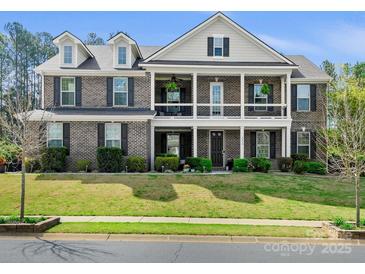 Stunning two-story brick home featuring a charming double porch and well-manicured lawn at 8618 Whitehawk Hill Rd, Waxhaw, NC 28173