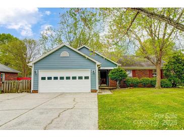 Charming single-story home with a blue exterior, well-manicured lawn, and attached two car garage at 13417 Krislyn Woods Pl, Charlotte, NC 28278