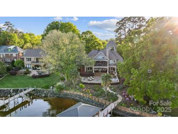 Stunning lakefront home featuring lush landscaping, a private dock, and an inviting outdoor patio at 20428 Island Forest Dr, Cornelius, NC 28031