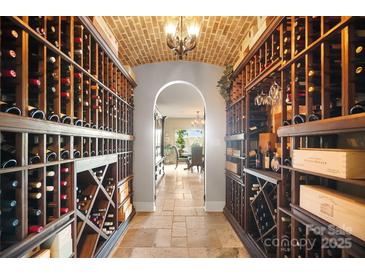 An elegant wine cellar with brick ceiling and custom wood shelving units is stocked with wines at 20428 Island Forest Dr, Cornelius, NC 28031