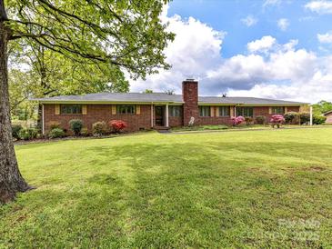 Charming brick home featuring a lush green lawn and meticulously landscaped front yard with mature trees at 225 Enwood Dr, Charlotte, NC 28214