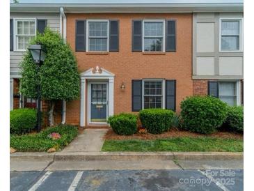 Charming brick townhome featuring black shutters, a well-manicured yard, and a welcoming blue front door at 4607 Hedgemore Dr # D, Charlotte, NC 28209