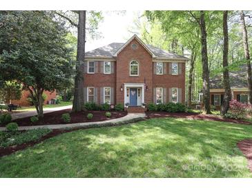 Charming two-story red brick home featuring a lush green lawn and mature trees at 6910 Green Turtle Dr, Charlotte, NC 28210