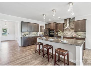 Modern kitchen boasts wood floors, granite countertops, and a large island with barstool seating at 8715 Gladden Hill Ln, Fort Mill, SC 29715