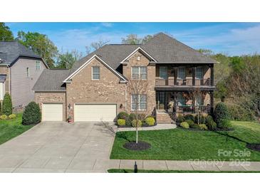 Charming brick home featuring a well-manicured lawn and inviting front porch and a three car garage at 10643 Rippling Stream Nw Dr, Concord, NC 28027