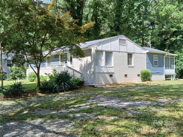 Charming single-story home with white brick, light blue siding, and a well-manicured lawn surrounded by mature trees at 2822 Royston Rd, Charlotte, NC 28208