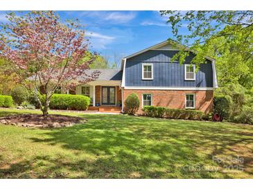 Charming two-story home with a brick facade and a well-manicured lawn, complemented by mature trees at 4937 Broken Saddle Ln, Charlotte, NC 28226