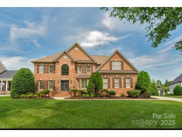 Traditional two-story brick home with well-manicured lawn, mature trees, and shuttered windows at 9008 Skipaway Dr, Waxhaw, NC 28173
