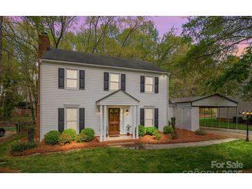 Charming two-story home with light siding, black shutters, manicured landscaping, and a detached carport at 9319 Harps Mill Ct, Charlotte, NC 28270