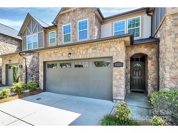 Beautiful stone-accented townhome with an attached two-car garage, manicured landscaping and an arched entryway at 9551 Glenburn Ln, Charlotte, NC 28278