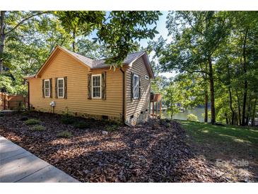 Cozy waterfront home with brown siding, white window trim, stone foundation, and mature trees at 119 Harbor Ln, Mount Gilead, NC 27306