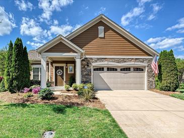 Charming home with a two-car garage, stone accents, well-maintained landscaping, and an inviting front porch at 1231 Restoration Dr, Marvin, NC 28173