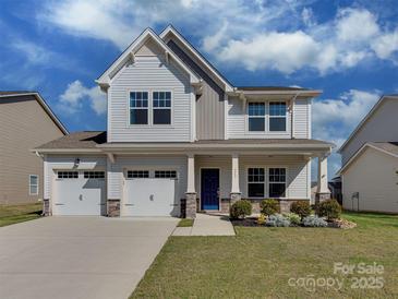 Charming two-story home boasts a three-car garage and a beautifully landscaped front yard with blue sky background at 317 Contentment Dr, Locust, NC 28097