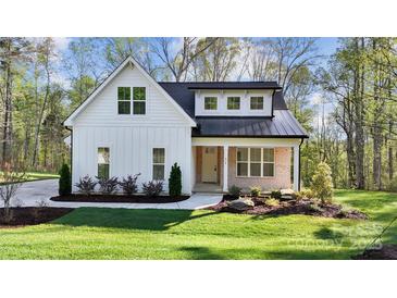Charming two-story farmhouse with white siding, black roof, manicured lawn, and inviting front porch at 472 Bellingshire Dr, Mt Ulla, NC 28125