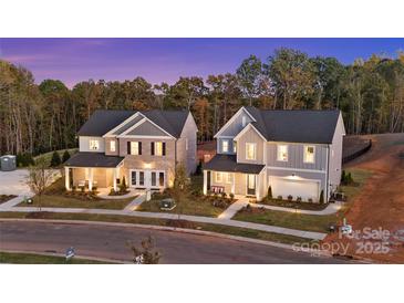 Two beautiful new construction homes with manicured lawns on a peaceful street at dusk at 7105 Short Stirrup Ln, Mint Hill, NC 28227
