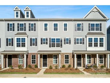 Three-story townhome exterior with brick accents, dark shutters and gray siding under a clear blue sky at 7117 Brookview Ln, Sherrills Ford, NC 28673