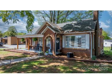 Quaint brick home featuring a covered front porch with rocking chairs and tidy landscaping at 2701 N Main Ave, Newton, NC 28658