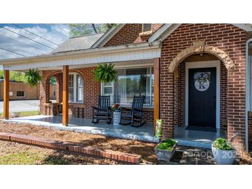 Charming brick home with a covered front porch featuring rocking chairs and hanging plants at 2701 N Main Ave, Newton, NC 28658