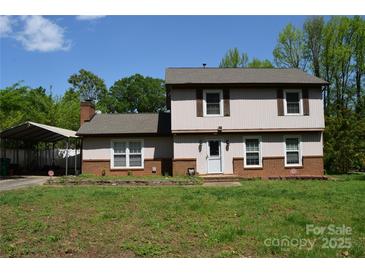 Charming two-story home with a lovely front lawn and a covered carport on a sunny day at 5915 Bluebonnet Rd, Charlotte, NC 28212