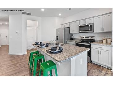 Bright kitchen features granite counters, stainless appliances and convenient island with bar stool seating at 729 Wagon Cross Ct, York, SC 29745